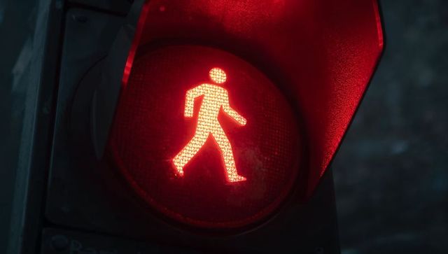 Red pedestrian walk signal glowing at night on urban crosswalk led pictogram