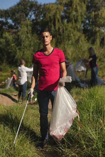 Male volunteer participating in a forest cleanup, holding a rubbish bag and grabber. Ideal for illustrating concepts of environmental protection, community service, and social responsibility. Suitable for campaigns promoting conservation, sustainable living, and outdoor activities.
