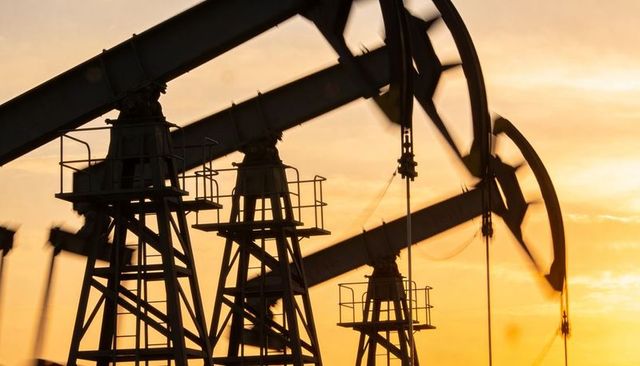 Silhouetted oil pumpjacks pumping at sunset in rural field