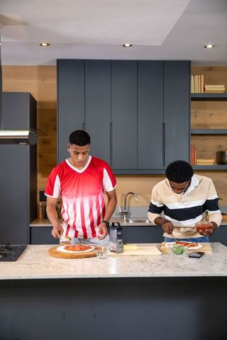 Diverse Friends Making Homemade Personal Pizzas in Modern Kitchen