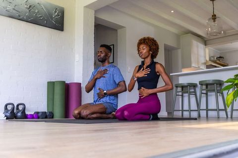 African american couple practicing mindful breathing and yoga at home for wellness