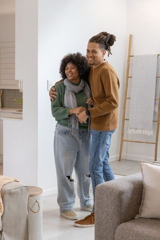Young couple embracing in cozy modern living room near open kitchen with neutral decor