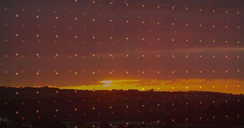 Vivid sunset over rural hills with digital pixelation