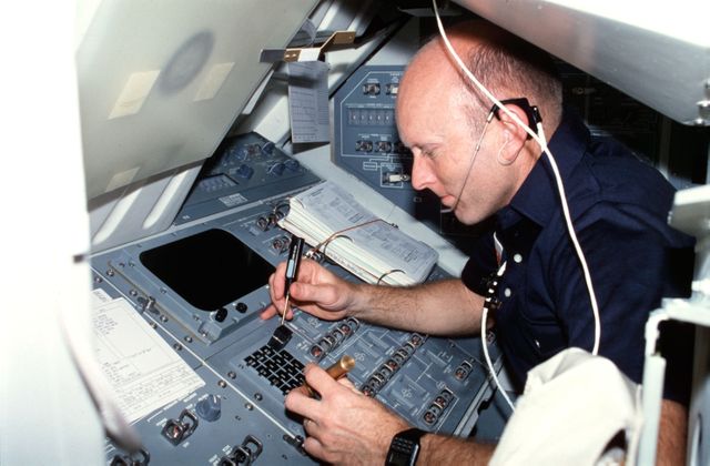 STS003-25-228 (22-30 March 1982) --- Astronaut Gordon Fullerton, STS-3 pilot, wearing communication kit assembly (ASSY) mini-headset (HDST) and using a screwdriver and flashlight (penlight), replaces acknowledge (ACK) key on aft flight deck mission station control panel R12L keyboard. Photo credit: NASA
