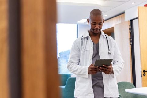 African american doctor using tablet in clinic corridor for digital patient records