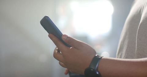 Hands Analyzing Mobile Analytics on Smartphone while Wearing Smartwatch with Backlit Bokeh