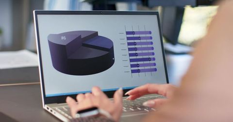 Young woman typing on laptop viewing 3d pie chart and bar graphs, wearing smartwatch