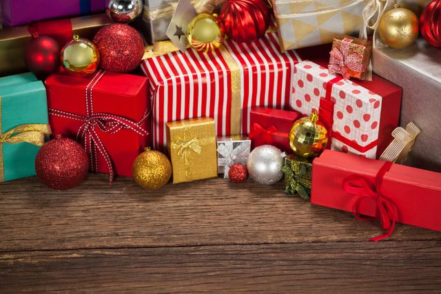 Wrapped gift boxes and baubles on wooden table during christmas time