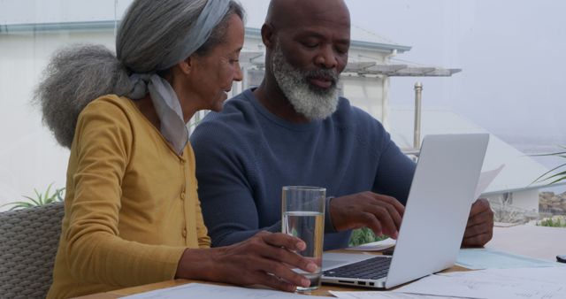 Biracial woman and African American man review documents at home. They're focused on managing finances or planning together in a domestic setting.