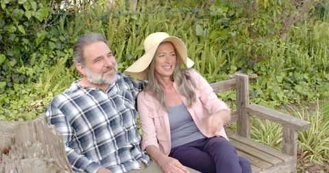 Senior Couple Relaxing Together on Bench in Sunny Garden