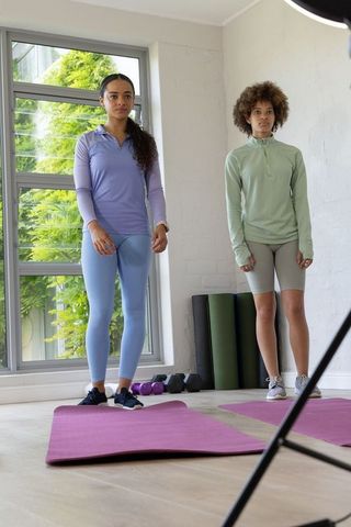 African women preparing for home workout on pink mats with dumbbells and greenery