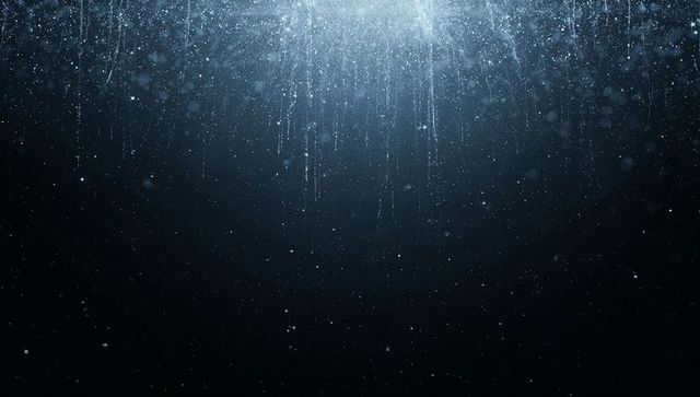 Streaming blue-white light shaft piercing deep ocean with suspended particles and glow