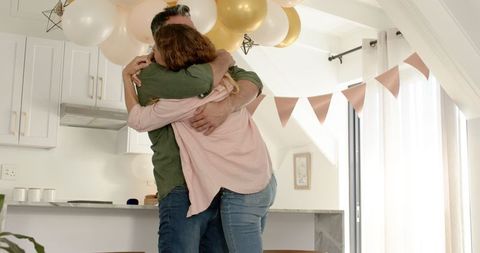 Mature Couple Joyfully Dancing in Festive Kitchen with Balloons