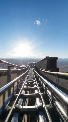 Roller coaster cart descending hillside rails toward sunrise panoramic valley view