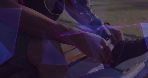 Adaptive athlete with prosthetic leg tying shoelaces outdoors