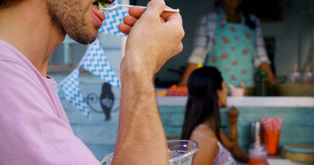 Young Man Enjoying Meal at Vibrant Outdoor Food Stall - Download Free Stock Images Pikwizard.com