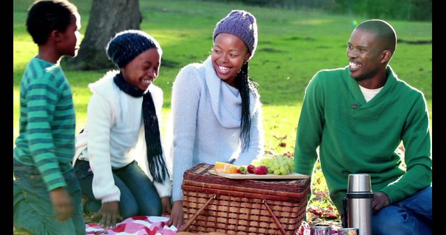 African American family enjoying a picnic in the park, with copy space. Smiling faces and a basket of fruit create a warm, joyful atmosphere.