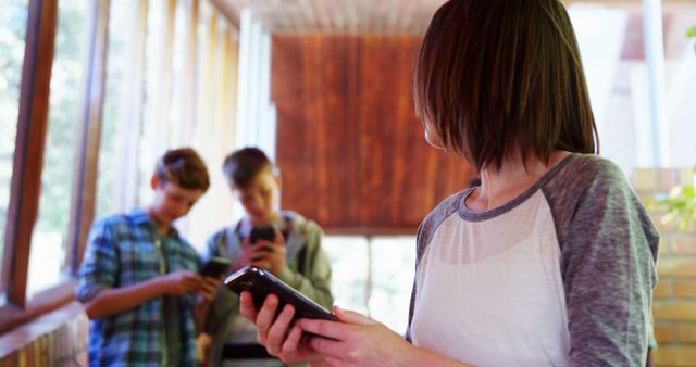 Teen Girl with Tablet Looking at Friends Using Smartphones Indoors - Download Free Stock Images Pikwizard.com