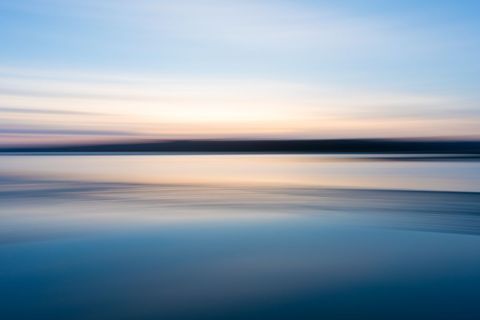 Serene Sunset Over Tranquil Water with Smooth Gradient Sky