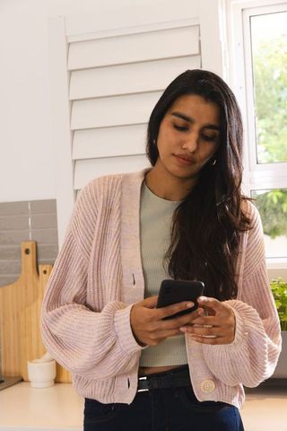 Asian 30s woman in modern kitchen holding smartphone