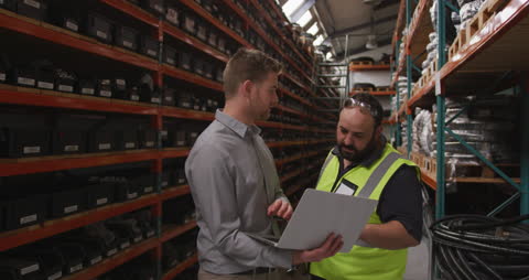 Warehouse Workers Discuss Production with Laptop