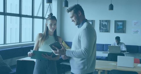 Coworkers Reviewing Tablet and Documents in Bright Modern Office Lounge