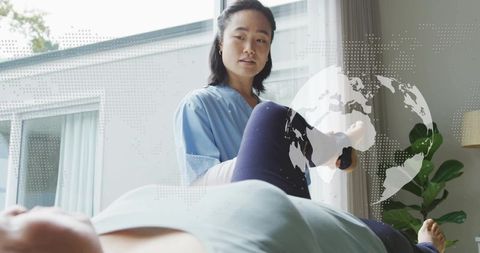 Korean physiotherapist supporting patient ankle stretch in modern home clinic