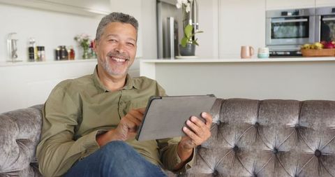 Senior man relaxing with tablet in modern living room