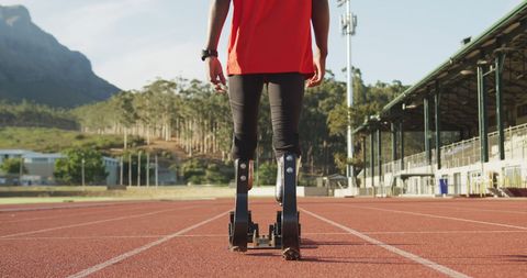 Athlete with Prosthetic Legs on Track Preparing for Training