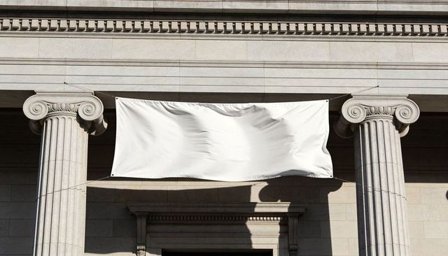 Blank white banner billowing between ionic columns on neoclassical stone facade