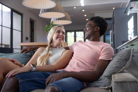 Multicultural couple relaxing on sofa in modern living room