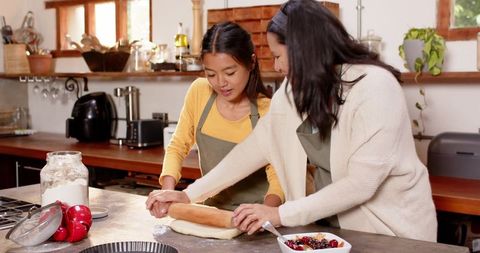 Mother and daughter bonding while rolling dough in cozy kitchen