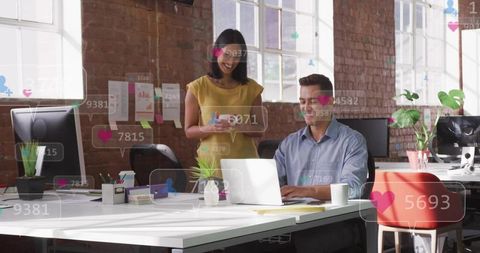 Young professionals collaborating in bright open-plan office with laptop and tablet