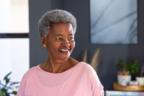 Senior woman smiling in sunlit minimalist home interior, serene lifestyle portrait