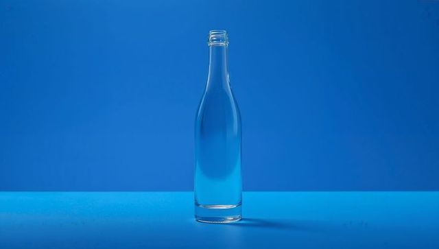 Minimalist transparent bottle on bright blue background