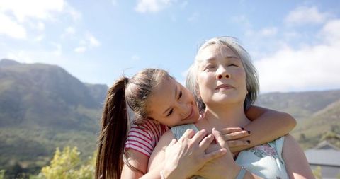 Granddaughter Hugging Asian Grandmother in Mountainous Scenery