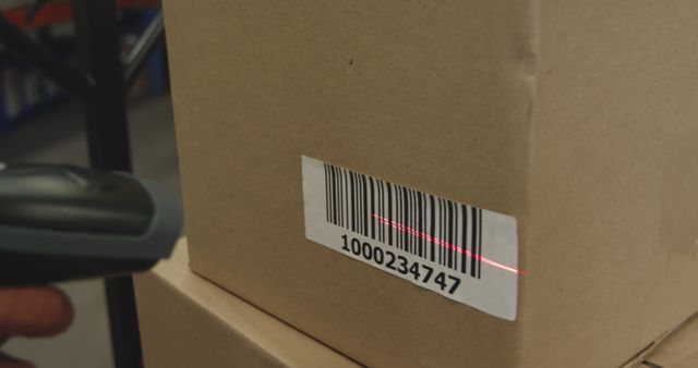Close up of the hand of a warehouse worker using a barcode reader to scan a barcode label on a cardboard box in a warehouse 