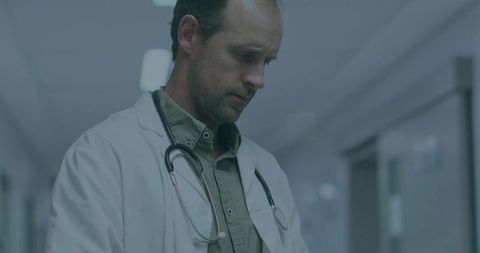Male doctor in hospital corridor with stethoscope