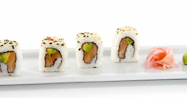 A row of sushi rolls with avocado and fish fillings is presented neatly on a white plate, with copy space. Sushi, a traditional Japanese dish, is often enjoyed for its fresh ingredients and artistic presentation.
