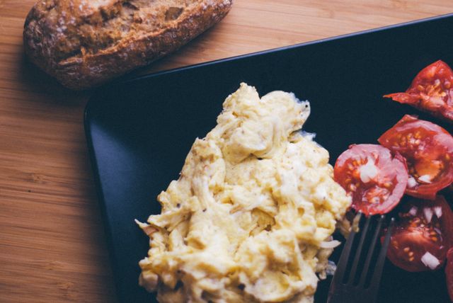 Scrambled Eggs with Sliced Tomatoes and Bread on Wooden Table - Download Free Stock Photos Pikwizard.com