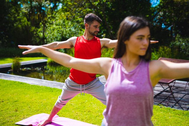 Young Caucasian man and woman practicing yoga poses on a sunny day in a lush green outdoor setting. Ideal for promoting fitness, wellness, and healthy lifestyle content. Suitable for use in articles, blogs, and advertisements related to yoga, outdoor activities, and physical health.