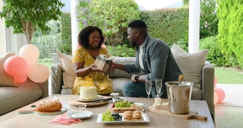 Couple Celebrating Birthday on Patio with Gift Exchange and Snacks
