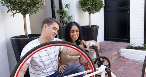 Diverse Couple Repairing Bicycle Wheel Outdoors