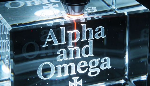 Laser engraving crystal block revealing frosted alpha and omega typography with cross