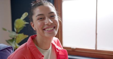 Smiling Teenage Girl Sitting by a Sunny Window Indoors