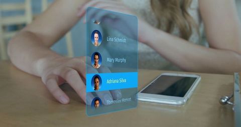 Young Woman Tapping Smartphone with Floating Holographic Contact List on Wooden Desk