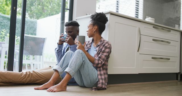 Image of happy african american couple drinking coffee and talking at home. love, relationship, togetherness and spending quality time at home.