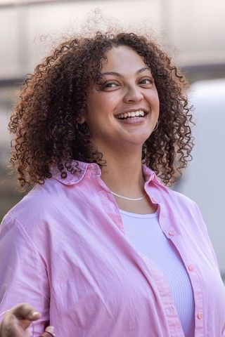 African american woman smiling outdoors in pink shirt | candid cheerful urban portrait