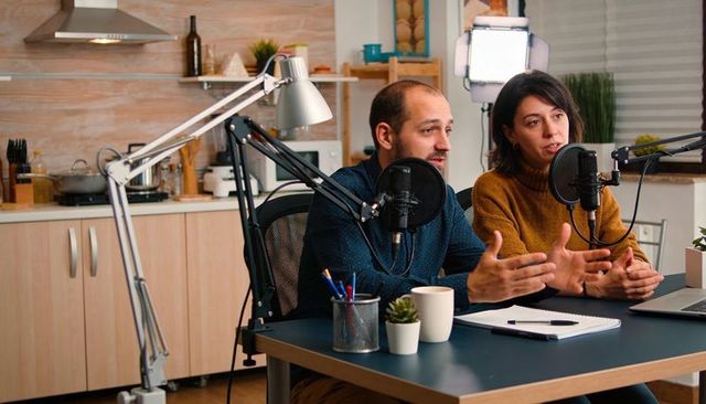Couple recording home podcast in kitchen studio with professional microphones
