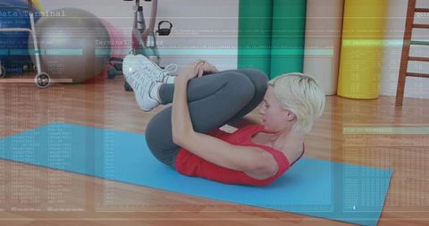 Woman performing knee hug exercise on mat in fitness studio for core strength training